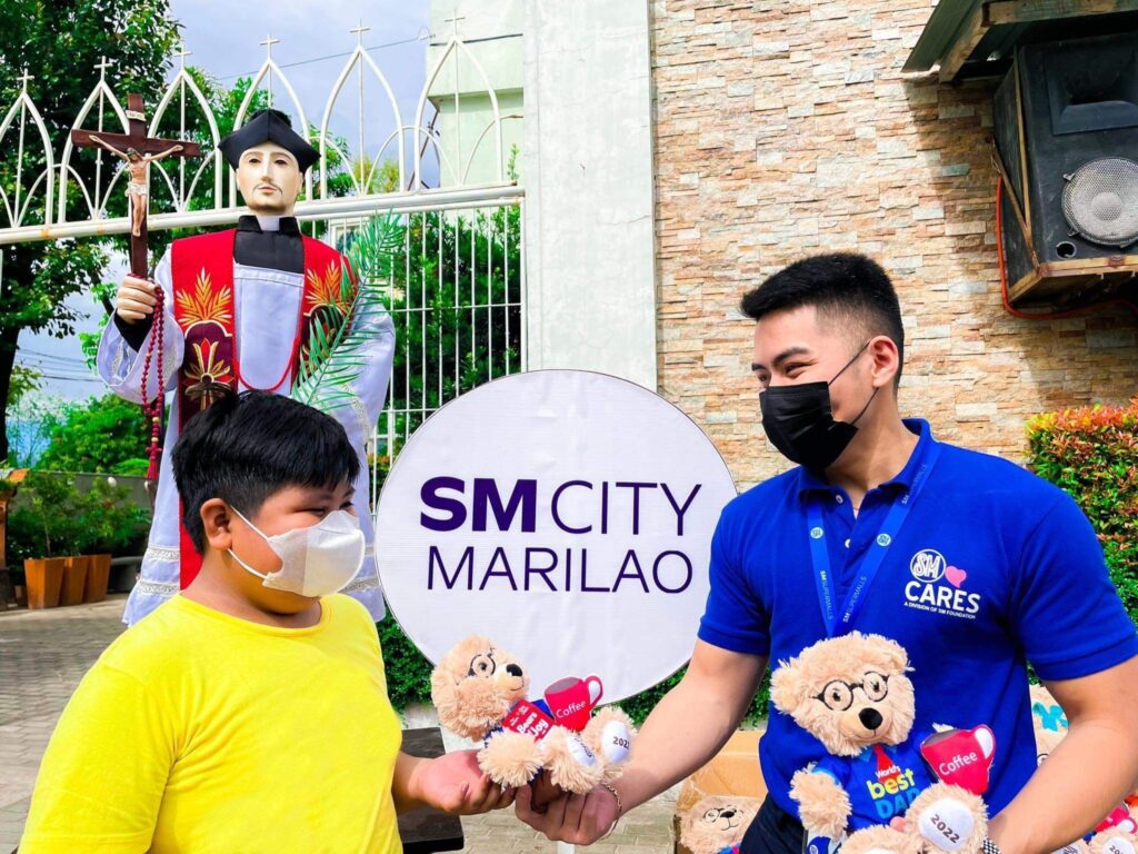 A volunteer from SM City Marilao is all smiles as he gives SM Bears of Joy to a kid. SM City Marilao caps 2022 with SM Bears of Joy Donation. The bear plushies donation brought smiles to 450 less fortunate children in the communities and orphanages in Bulacan. An annual project of SM Cares, SM Supermalls, and Toy Kingdom, SM Bears of Joy intends to bring much-needed smiles to children during the Christmas season and allow SM’s community of shoppers to contribute to spreading joy and charity to other people.