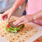 Woman hands wrapping a healthy sandwich in beeswax food wrap